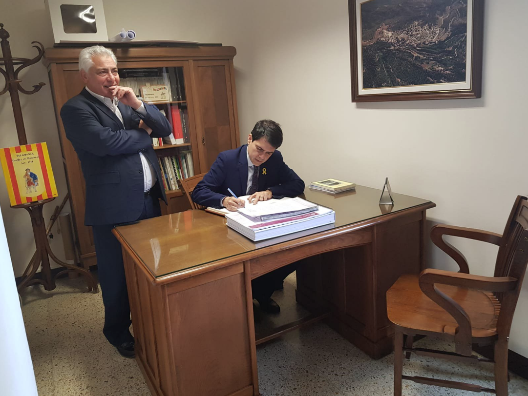 Tarín, de pie, mientras el presidente de la Diputación de Barcelona, Marc Castells, firma el libro de honor del Ayuntamiento de Talamanca