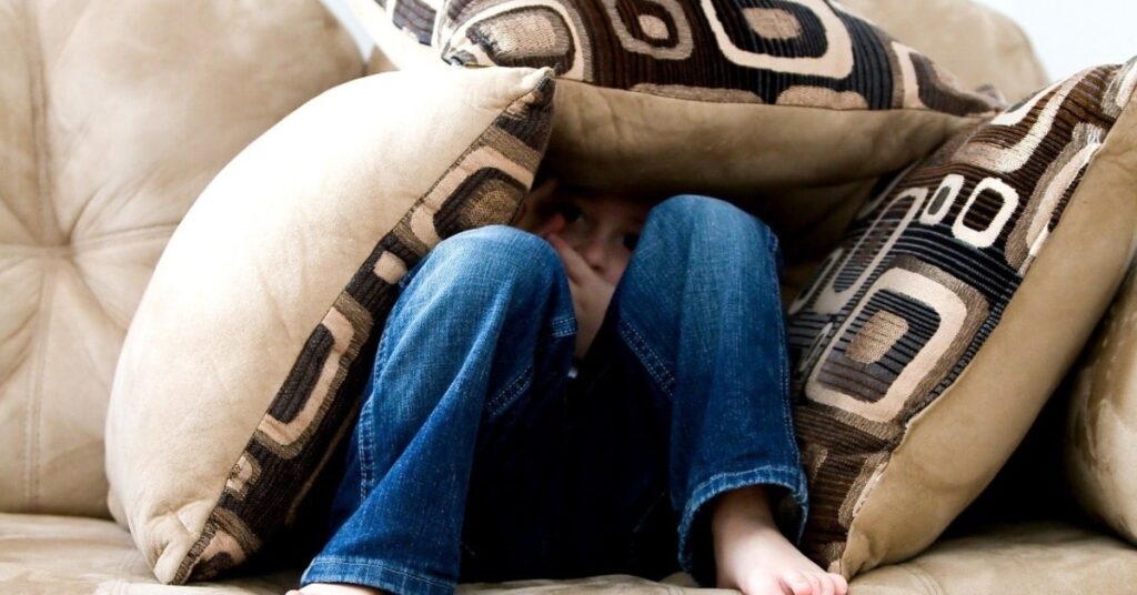 Niño escondido entre cojines (ambermb, Pixabay)