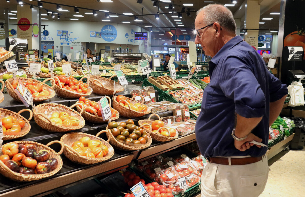 Un home compara els preus de la verdura en un supermercat (ACN)