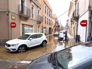 Un coche sale de una calle anegada de agua en la Bisbal d'Empordà después de una tormenta