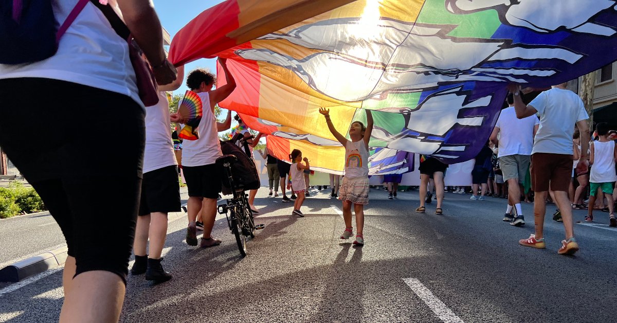 Dos niñas juegan bajo una bandera multicolor durante el Pride Barcelona (Laura Busquets, ACN)
