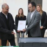 El director general de Memoria Democrática, Alfons Aragoneses, entrega el informe de identificación de Narcís Mediavilla Cardó a sus nietos, frente a la caja que contiene los restos del soldado barcelonés (Eloi Tost, ACN)