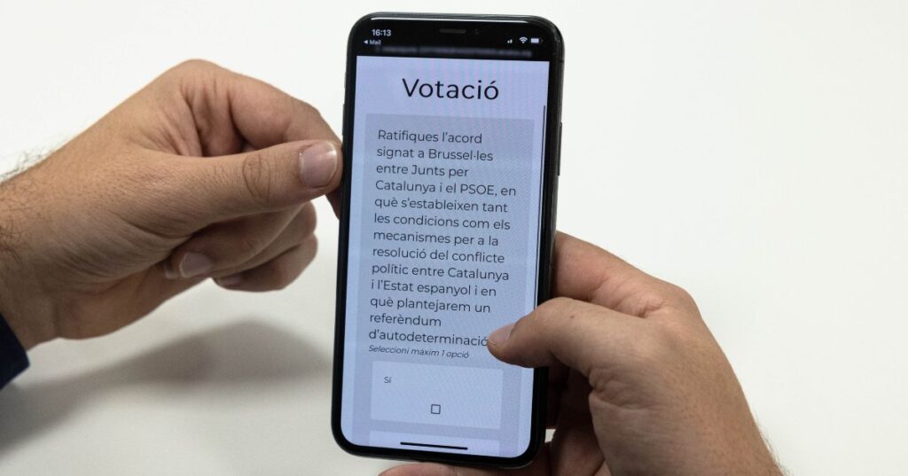 Un telèfon mòbil amb la pregunta que Junts ha fet a la militància sobre l'acord d'investidura amb el PSOE
