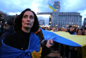 Una dona sosté una bandera d'Ucraïna amb altres manifestants a la plaça de Catalunya (Pau Cortina, ACN)