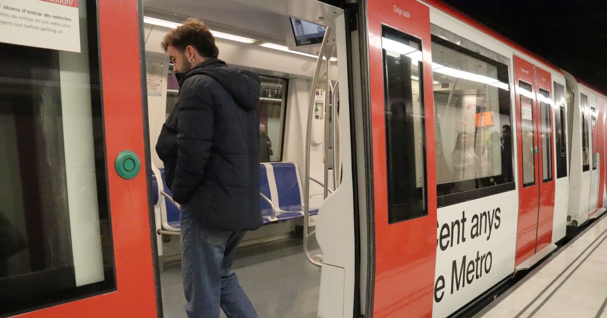 Un passatger puja a un metro decorat amb un vinil del Centenari del suburbà (ACN)