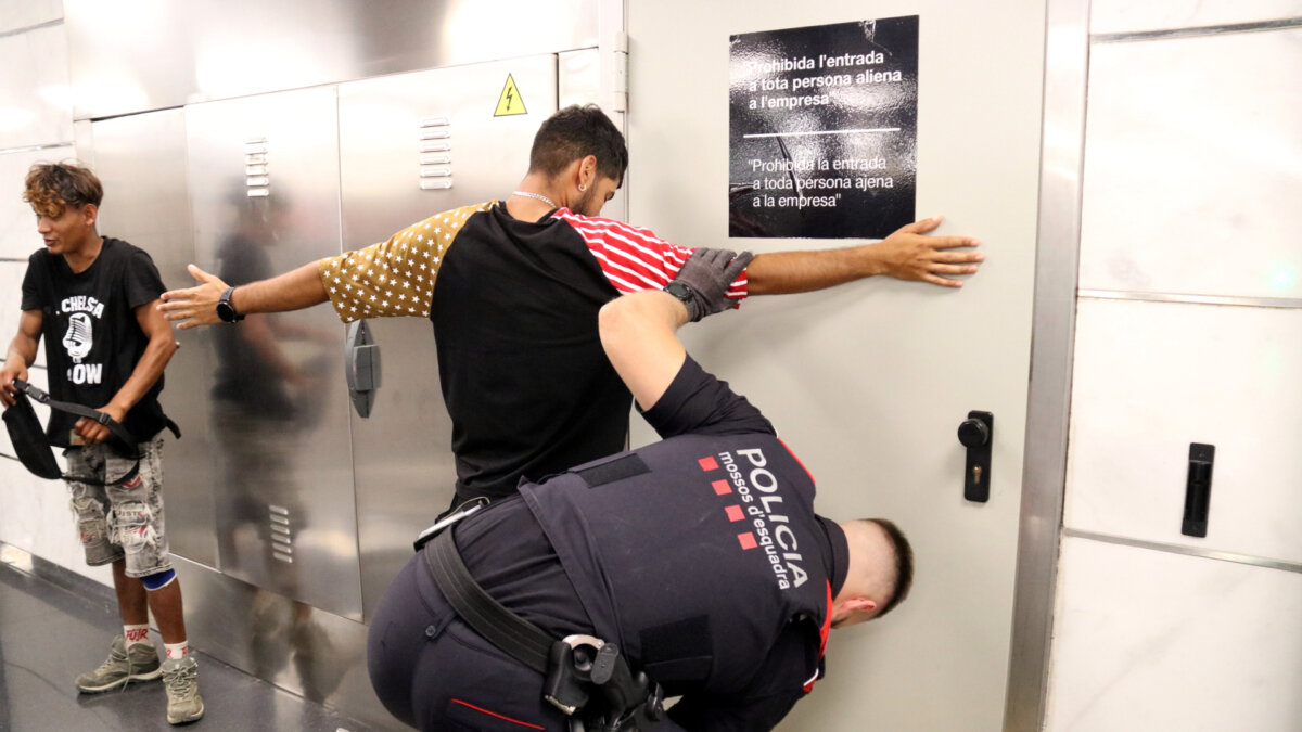 Un agente de los Mossos registrando a un hombre en la estación de la Sagrera (Àlex Recolons, ACN)
