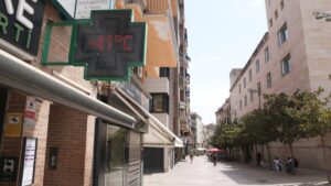Calle de Pi i Margall de Lleida con gente a la sombra y un termómetro que indica 41 grados (Ignasi Gómez, ACN)
