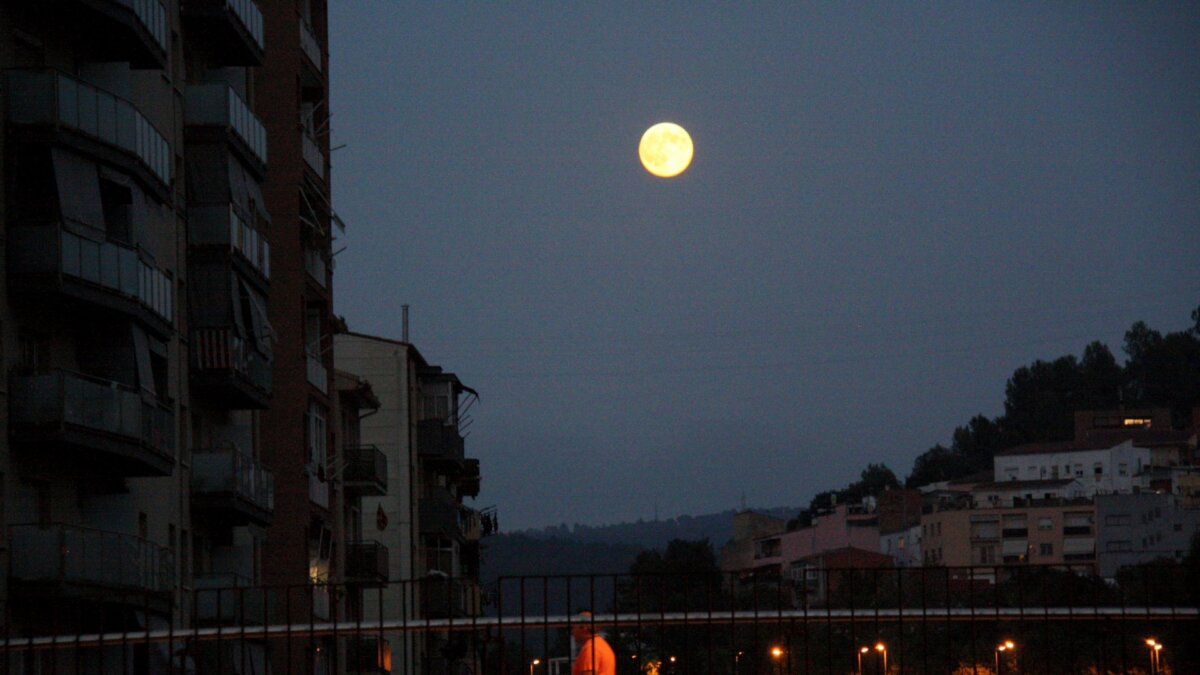 La luna saliendo entre unos edificios en la ciudad de Girona (Nerea Guisasola, ACN)