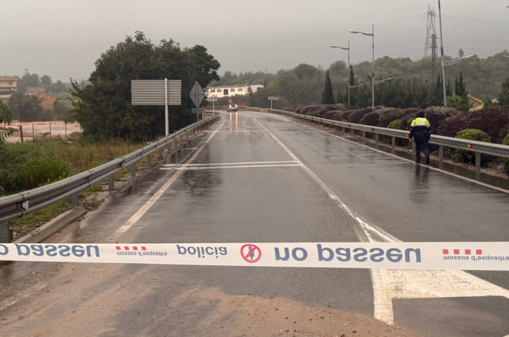 Carretera tallada per un temporal de pluges amb un agent de policia