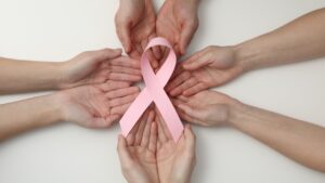 Mans sostenint un llaç rosa, símbol de la lluita contra el càncer de mama