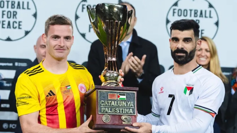 Dos jugadors sostenint un trofeu del partit Catalunya-Palestina.