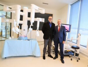 Dos persones al costat d'un robot quirúrgic a DFactory Barcelona.