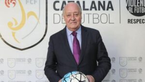 Joan Soteras amb una pilota de futbol davant del logo de la FCF.