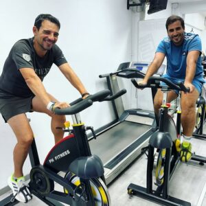 Dos homes fent exercici en bicicletes estàtiques al gimnàs