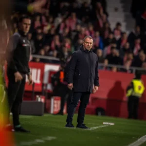 Hansi Flick observant el partit Girona-Barça amb preocupació
