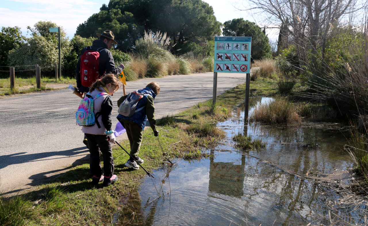 Tres de los participantes limpiando el margen de un camino (Àlex Recolons, ACN)