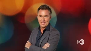 Xavi Valls presentant el programa ONZE de TV3 amb un fons colorit.