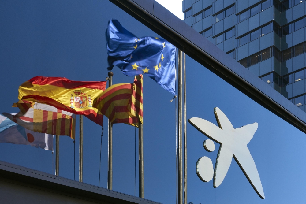 Imatge de la seu de CaixaBank amb banderes d'Espanya i Europa