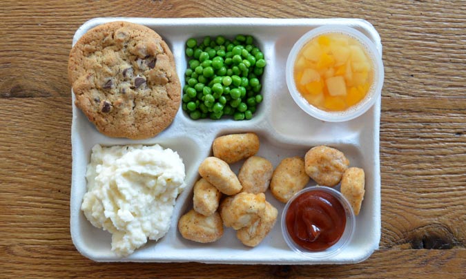 Menú escolar amb plats variats com pollastre, puré i galeta