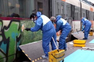 Tres operaris netegen un grafit d'un tren de Rodalies a l'Estació de França (Guifré Jordan, ACN)