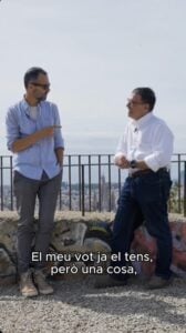 Dos hombres hablando sobre votaciones en Barcelona con vista de la ciudad