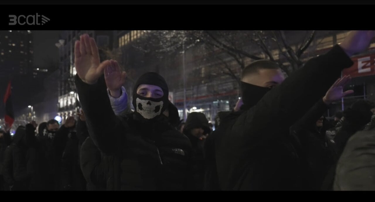 Manifestants amb gestos de suport a l'extrema dreta en una protesta nocturna.