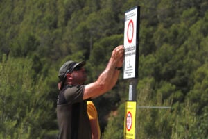 Un agent rural instal·lant un senyal de prohibició en un bosc